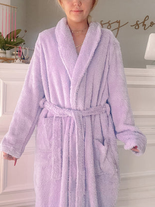 Soft lilac fuzzy robe with pockets and tie belt, shown on a model.
