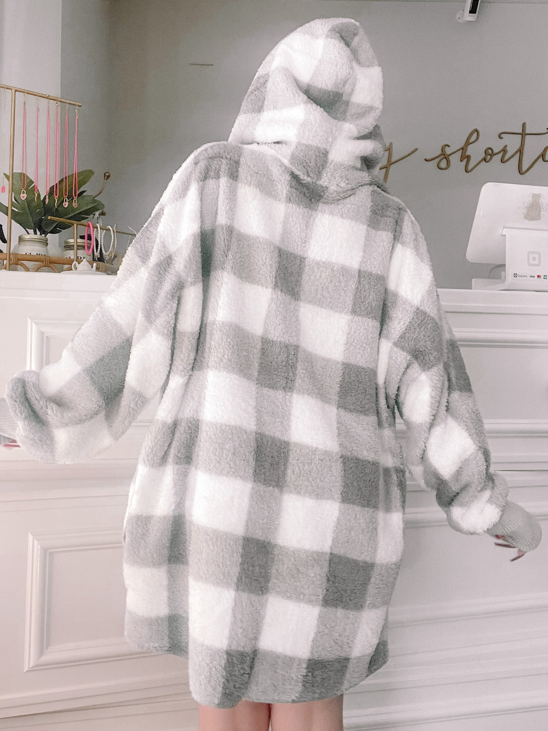 Grey and white fuzzy hooded jacket with buffalo plaid pattern, shown from the back.

