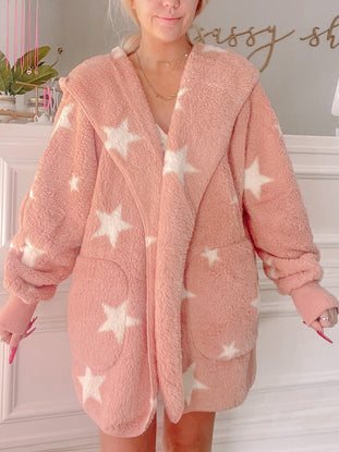 Pink fuzzy jacket with white stars, cozy hooded design.
