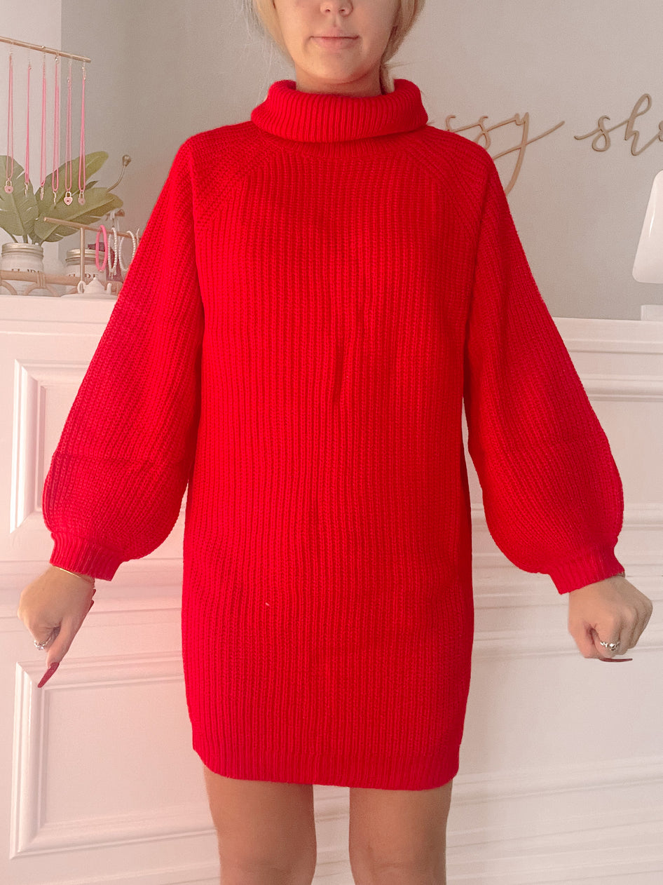 Red ribbed knit turtleneck sweater dress with balloon sleeves, shown on a model.
