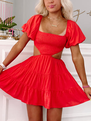 Red tiered mini dress with cutout detail and puff sleeves, shown on a model.
