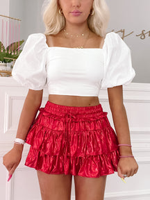 Red tiered mini skirt with white puff-sleeve crop top.
