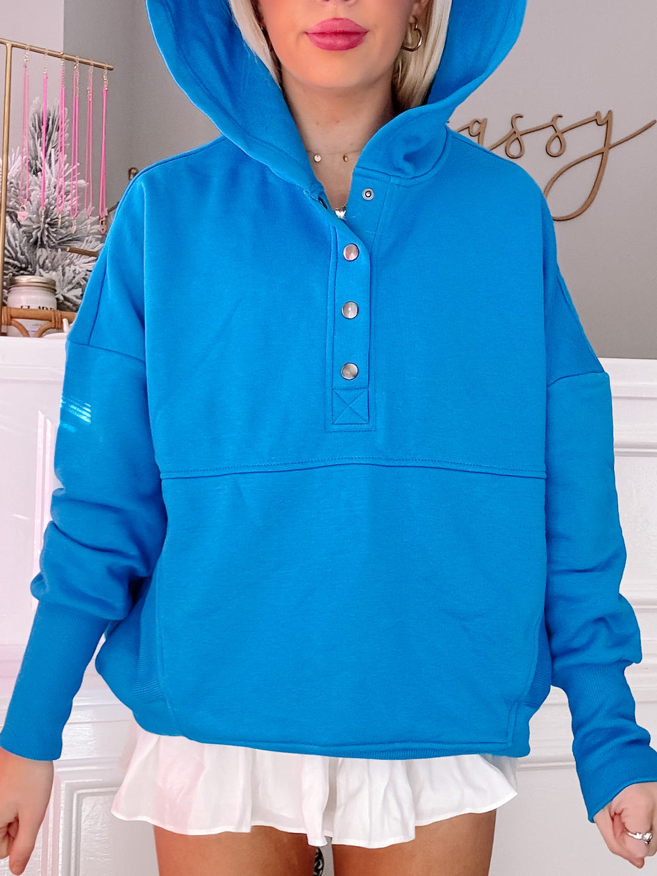 Bright blue hooded pullover with button placket, shown on model.

