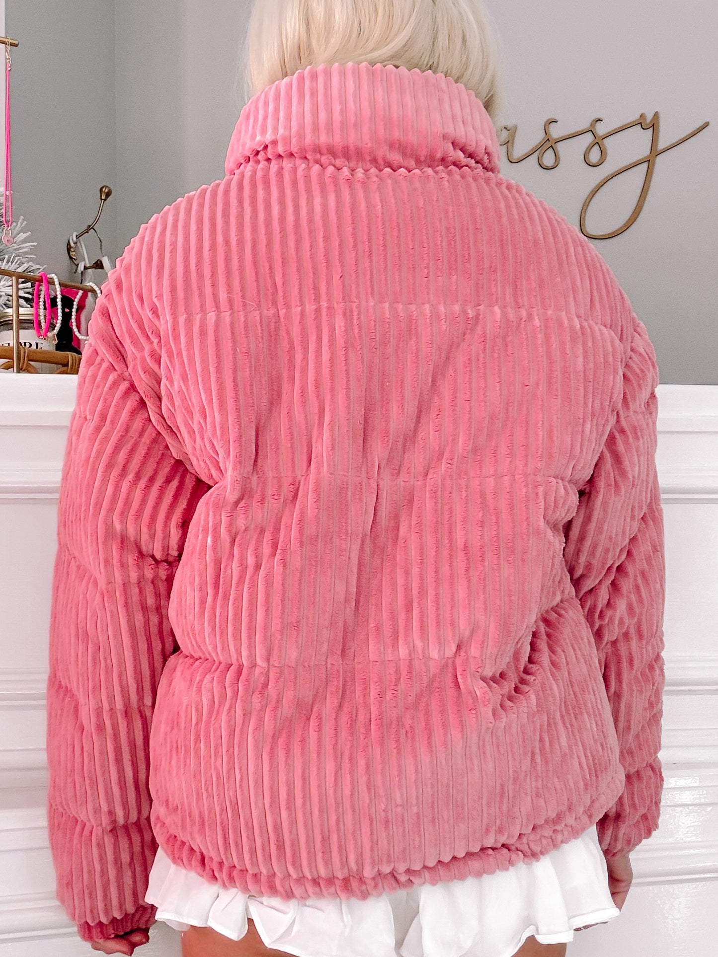 Pink corduroy puffer jacket, back view, ribbed texture.
