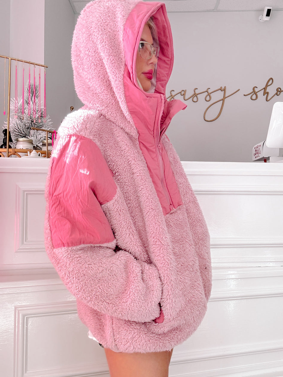 Pink sherpa pullover with a contrasting panel, shown on a model in a store.
