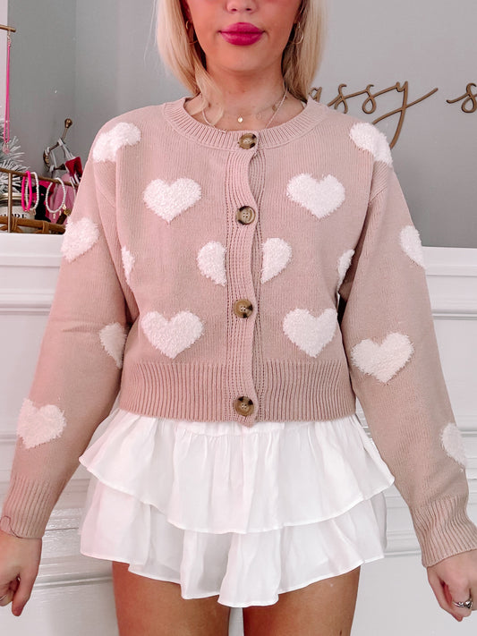 Dusty rose cardigan adorned with fluffy white hearts, button closure, modeled with white tiered skirt.