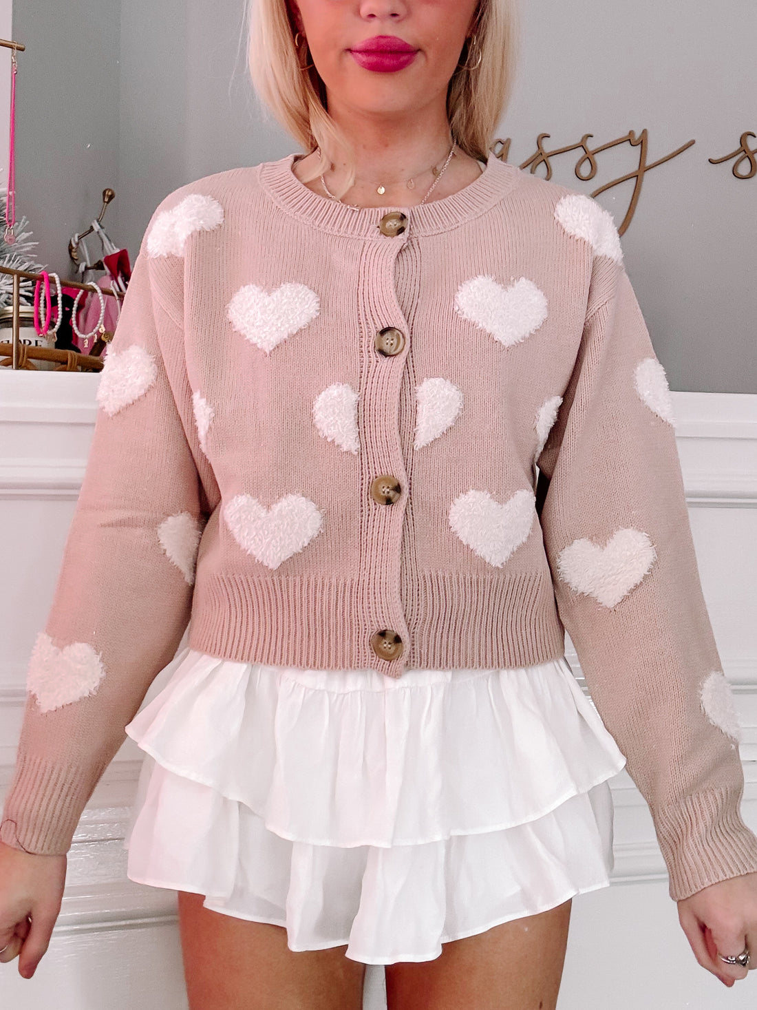 Dusty rose cardigan adorned with fluffy white hearts, button closure, modeled with white tiered skirt.
