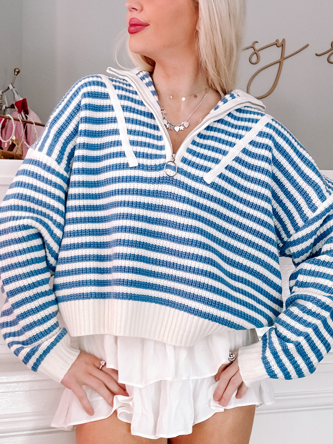Blue and white striped knit pullover, half-zip style, modeled on a person.
