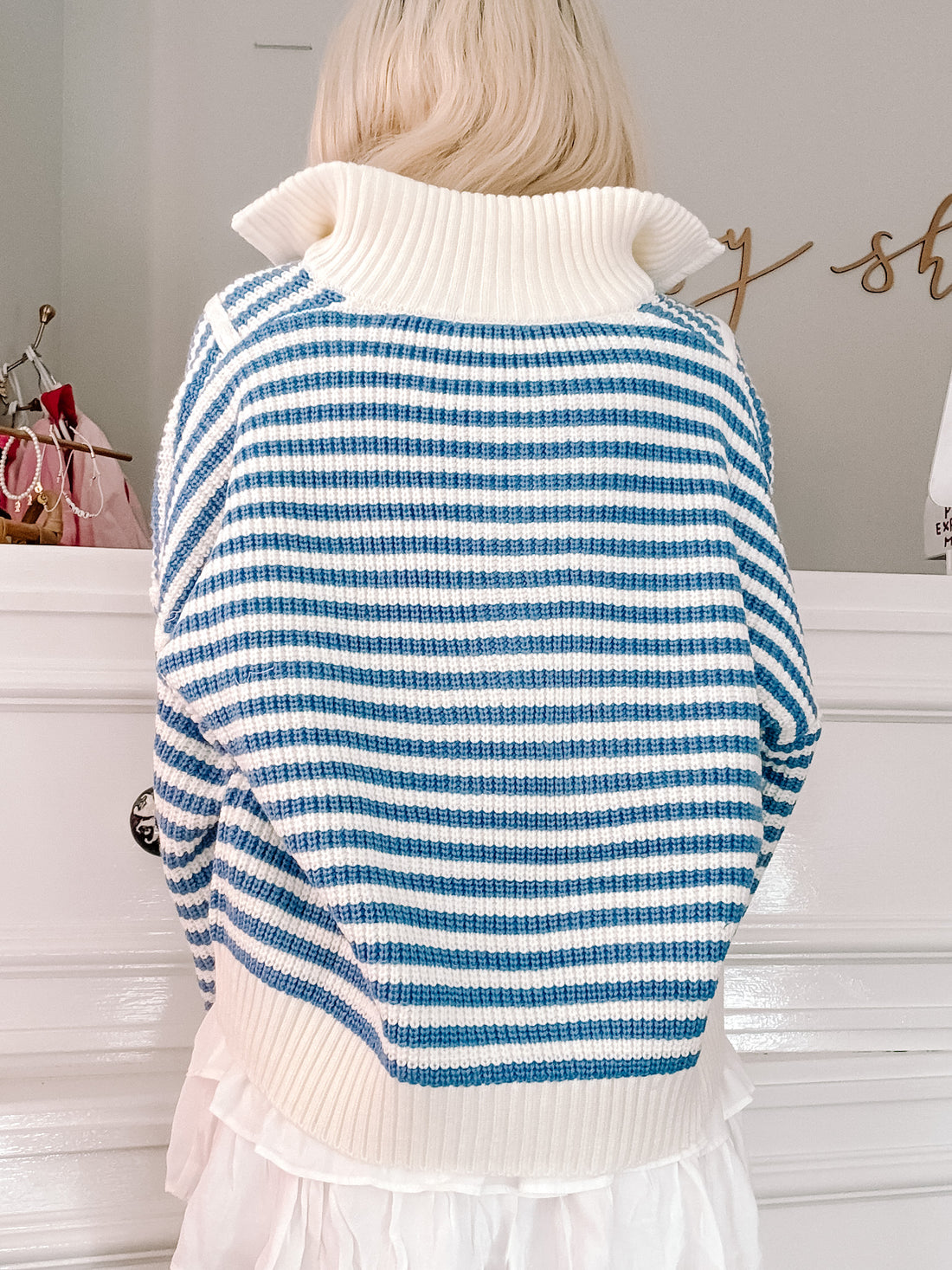 Blue and white striped turtleneck sweater, waffle knit texture,  worn over a white ruffle skirt.
