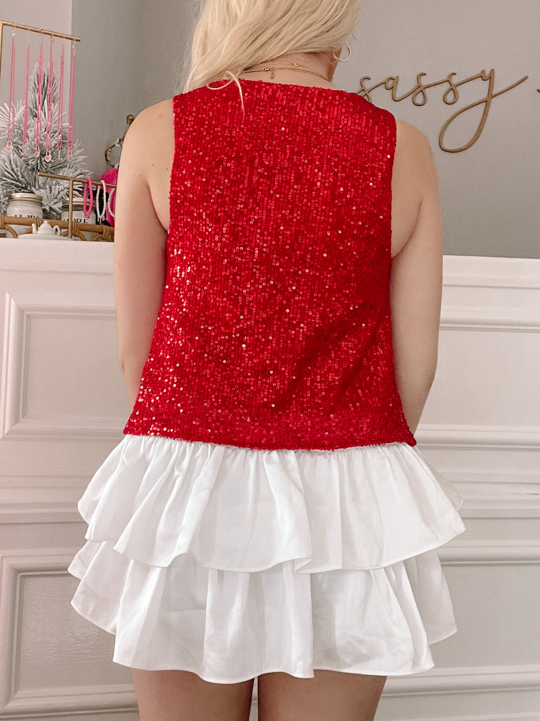 Red sequin sleeveless top paired with a white ruffled mini skirt, shown from the back against a neutral background.

