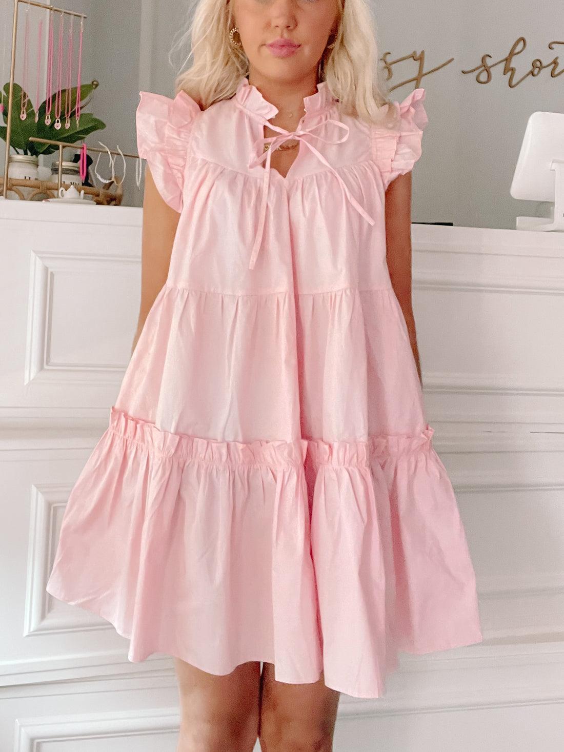 Pink tiered mini dress with ruffle sleeves and a keyhole neckline, shown on a model.
