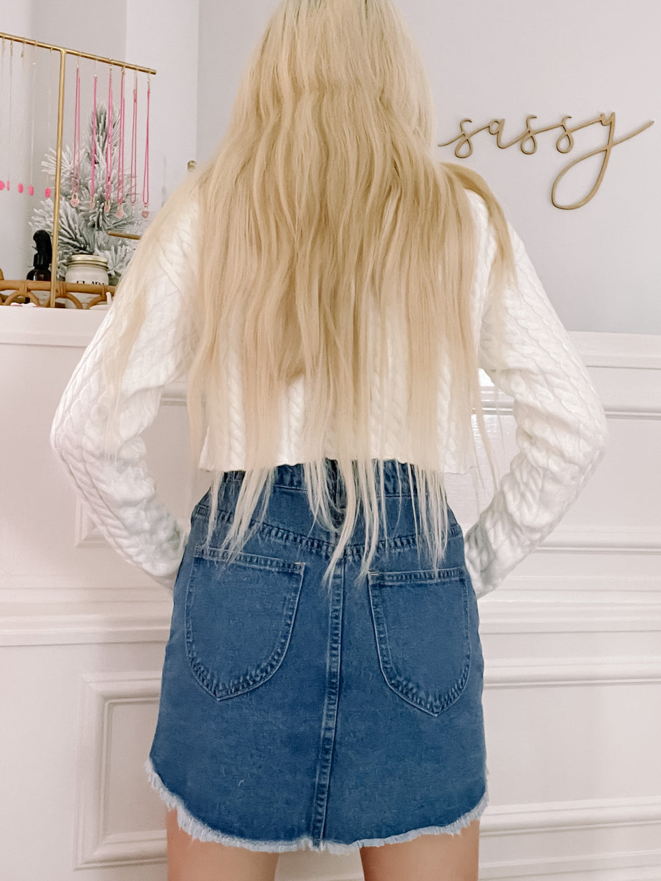 Dark wash denim mini skirt with frayed hem, shown from the back.
