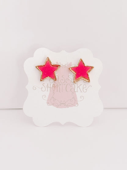 Pink star-shaped stud earrings with gold accents, displayed on a product card.
