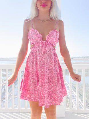 Pink mini dress with white star print, worn outdoors on a sunny day.

