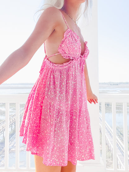 Pink mini dress with white star print, shown on a model near a waterfront balcony.
