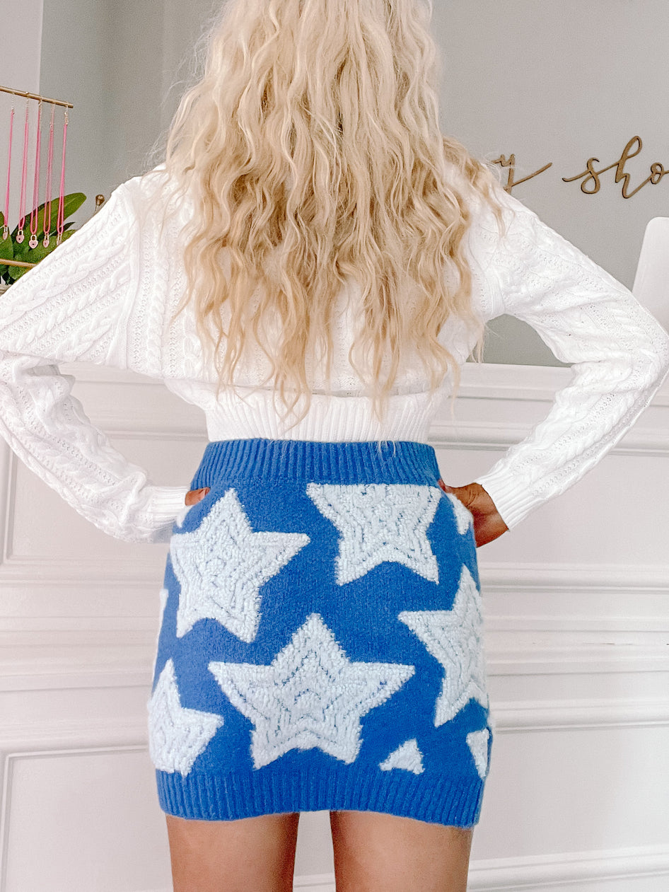 Cozy blue mini skirt featuring light blue star accents, modeled with a white sweater.
