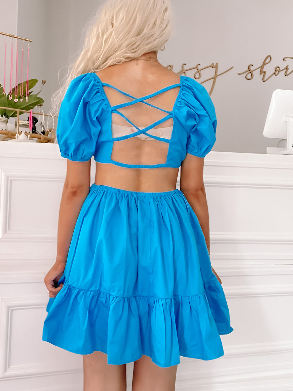 Bright blue summer dress with puff sleeves, crisscross back, and tiered skirt.
