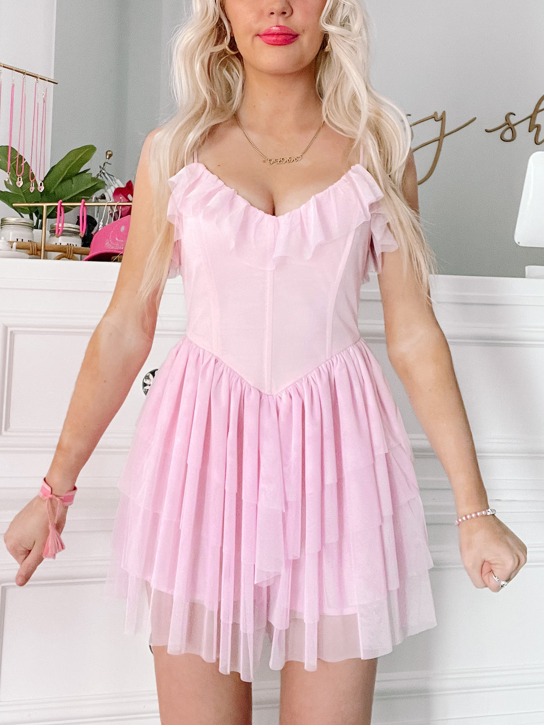 Pink layered tulle dress with ruffled bodice, shown on model in a light-colored room.
