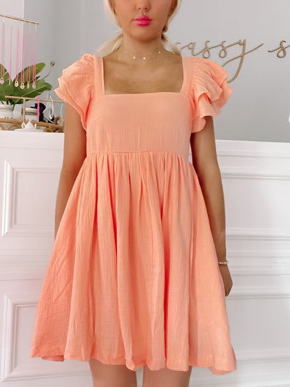 Peach mini dress with ruffled short sleeves and square neckline, shown on a model.
