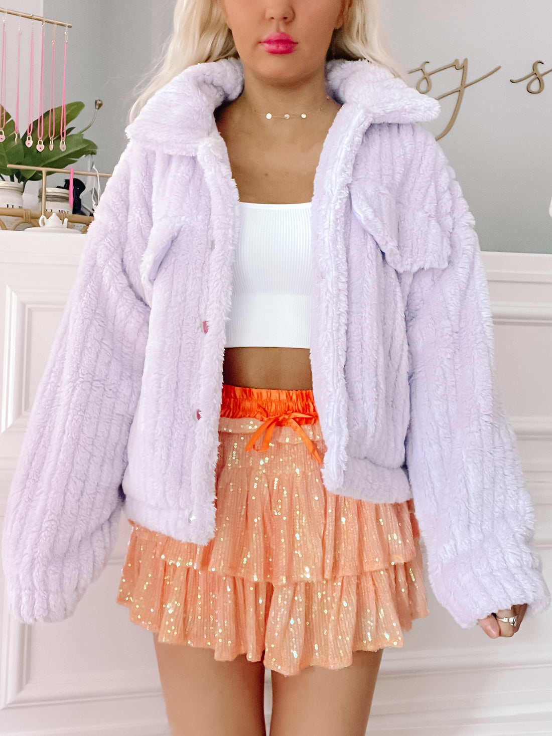 Lilac fluffy jacket styled with a peach sequined skirt.
