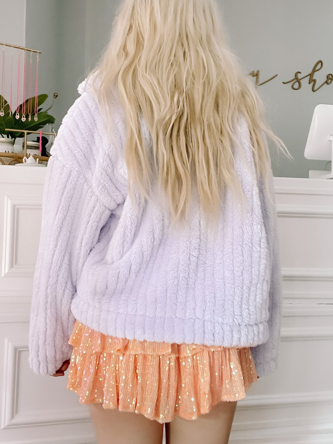 Lilac plush jacket shown from the back, paired with a sequined skirt.

