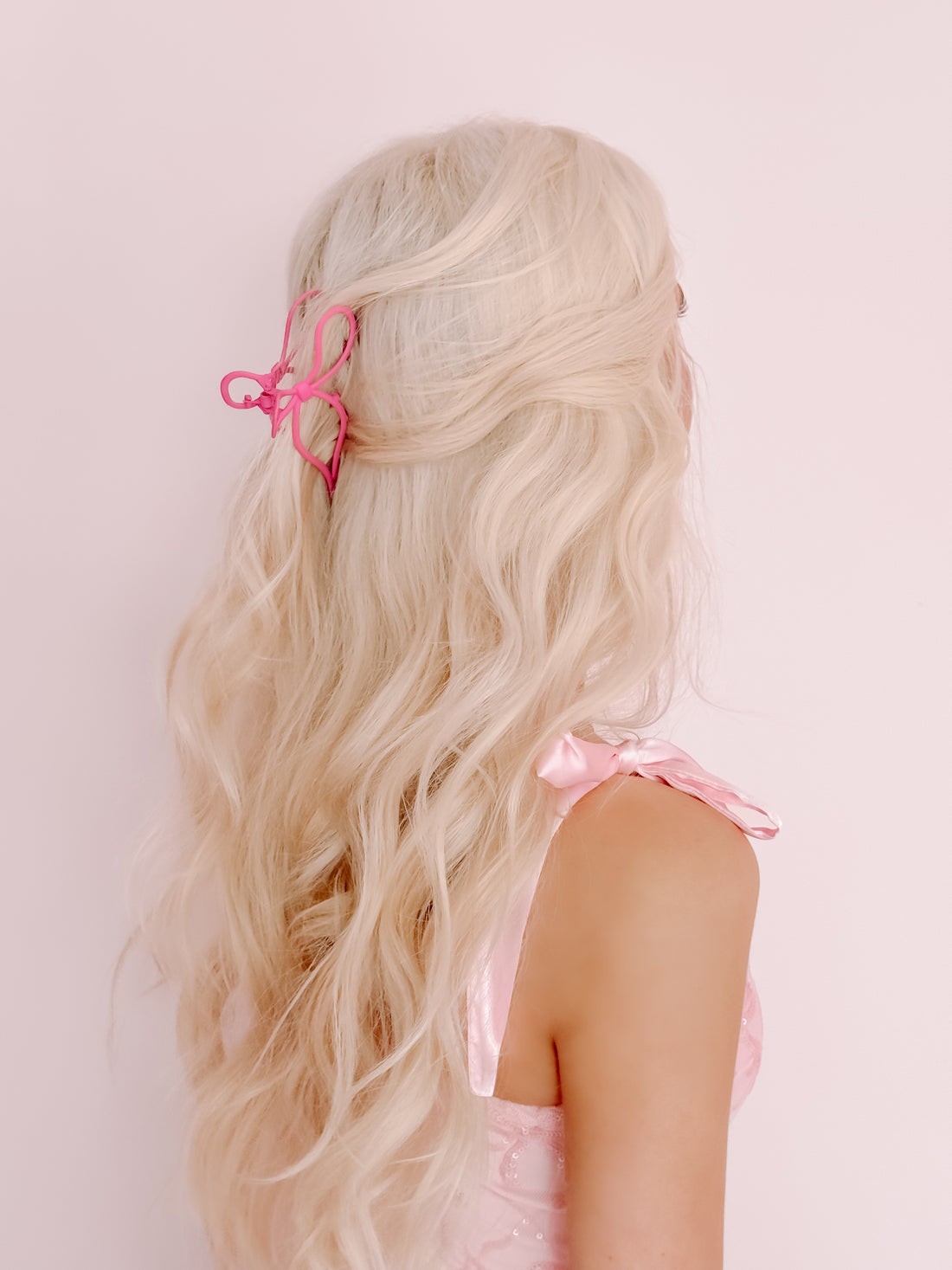 Pink claw hair clip in blonde wavy hair, styled for an elegant look.
