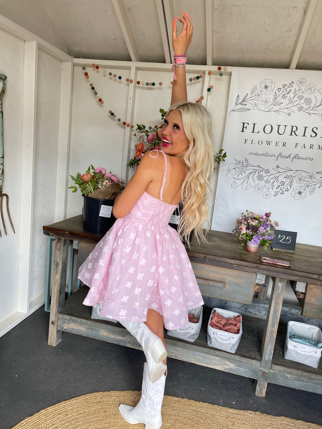 Blousey pink mini dress with floral embroidery, modeled outdoors at a flower farm.
