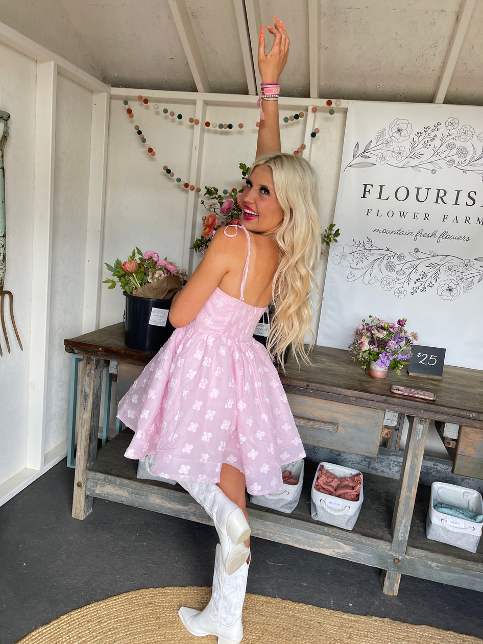 Blousey pink mini dress with floral embroidery, modeled outdoors at a flower farm.
