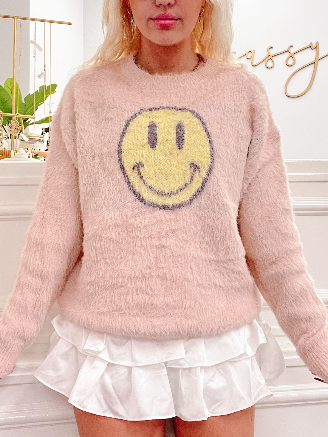 Pink fuzzy Warm Smiles sweater with yellow smiley face detail
