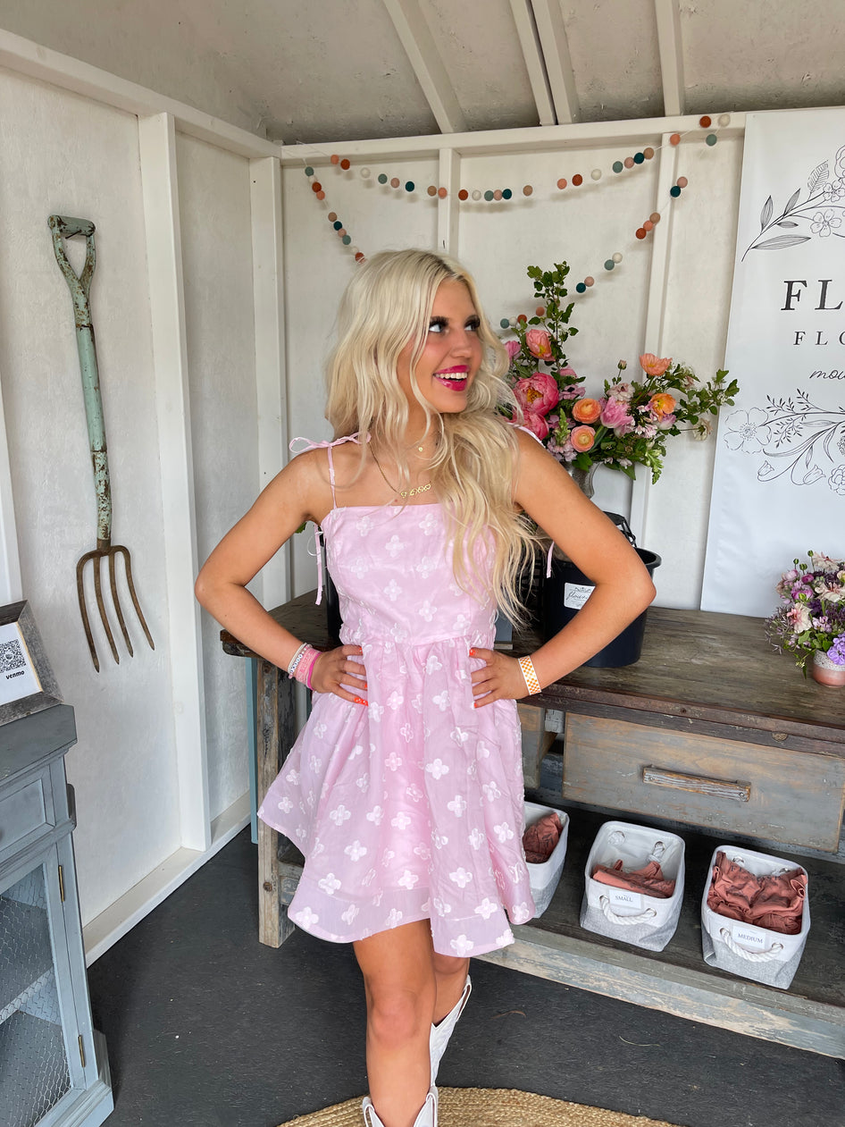 Pink floral mini dress, worn outdoors against a flower shop backdrop.
