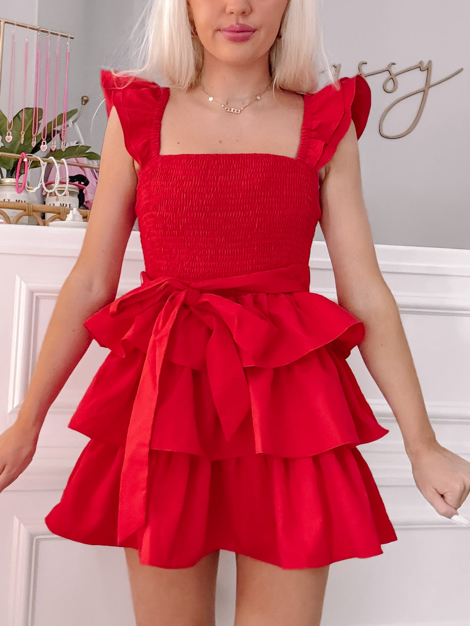 Red tiered mini dress with ruffle sleeves and a self-tie waist, shown on a model.
