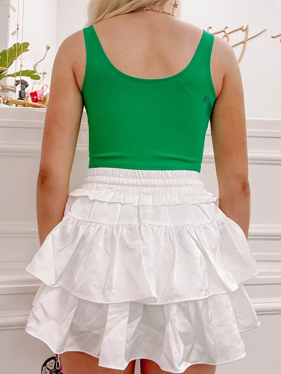 White tiered ruffle mini skirt, shown from behind against a bright background.
