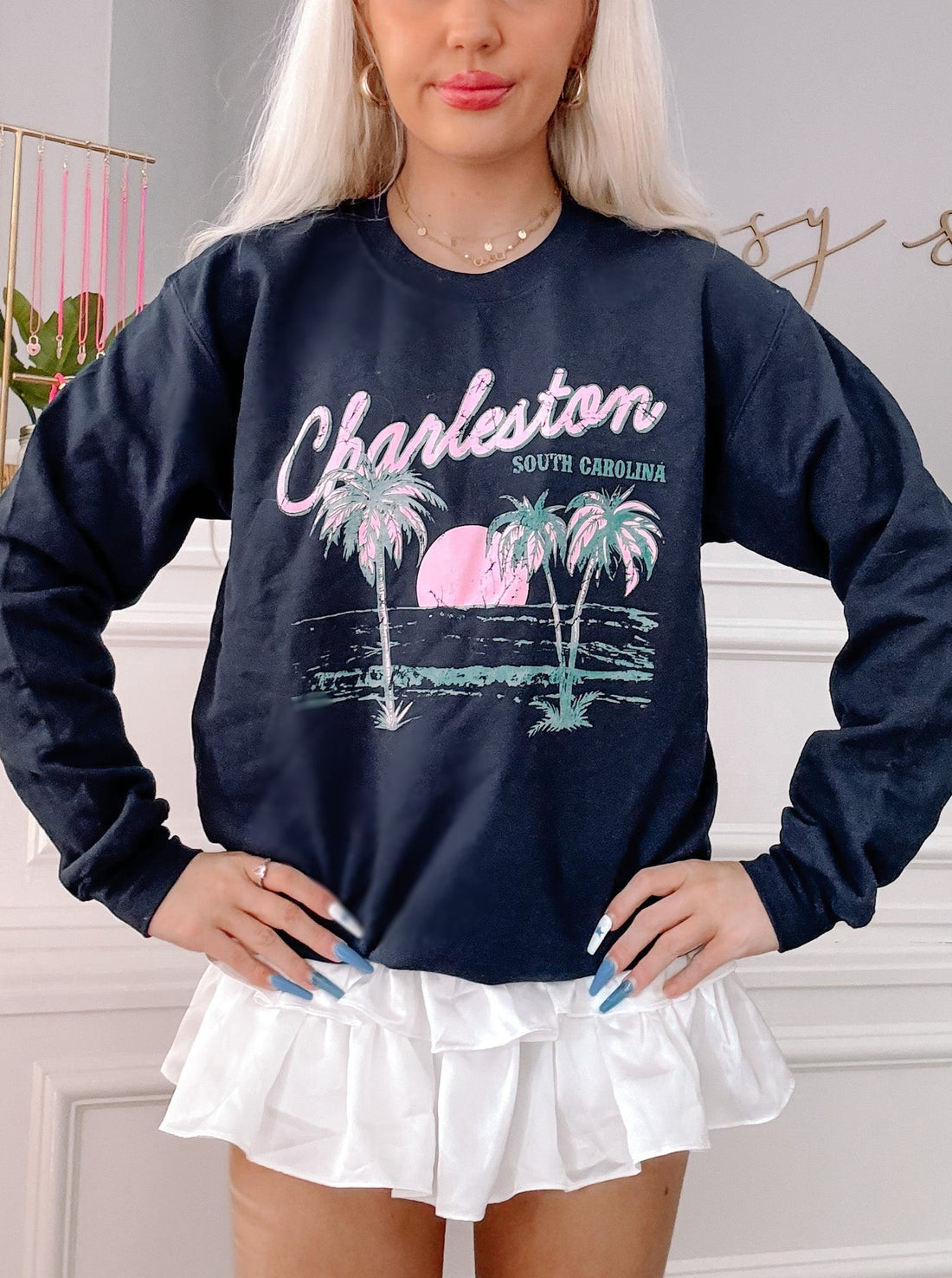 Navy blue crewneck sweatshirt featuring a Charleston, South Carolina design with palm trees and a sunset graphic.
