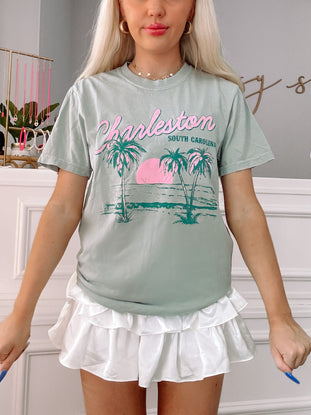 Charleston Tee | Green: Sage green tee featuring palm tree and sunset graphic; perfect for summer.
