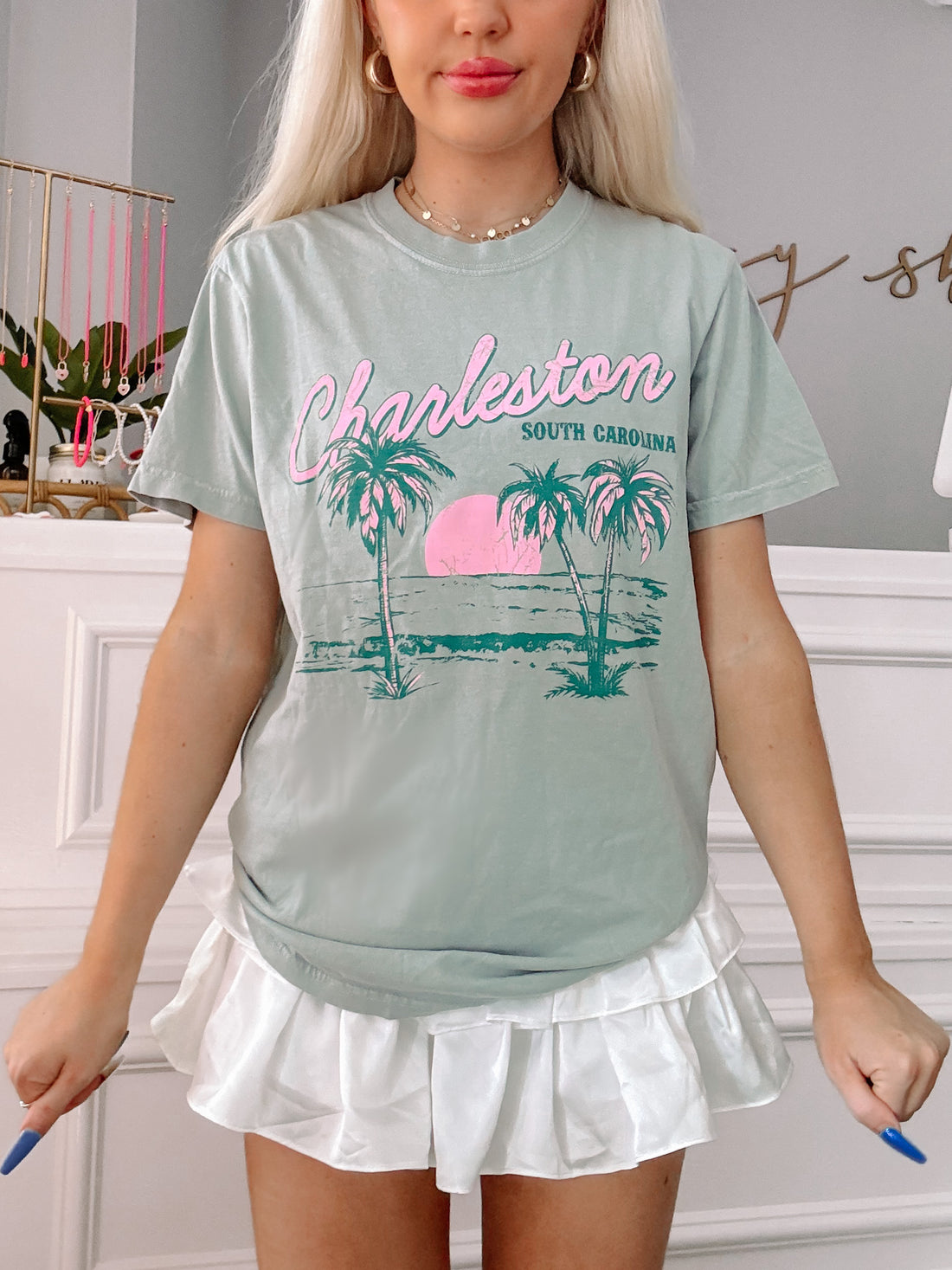 Sage green tee showcasing Charleston, South Carolina beach scene; palm trees & sunset graphic.
