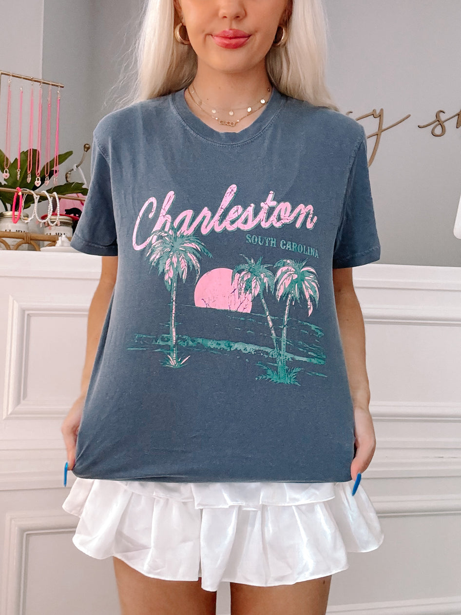 Slate grey tee showcasing a Charleston, South Carolina design with palm trees and sunset graphic.
