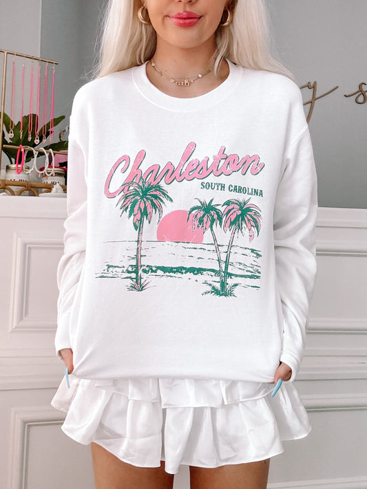 White crewneck sweatshirt featuring a Charleston, South Carolina beach scene graphic.