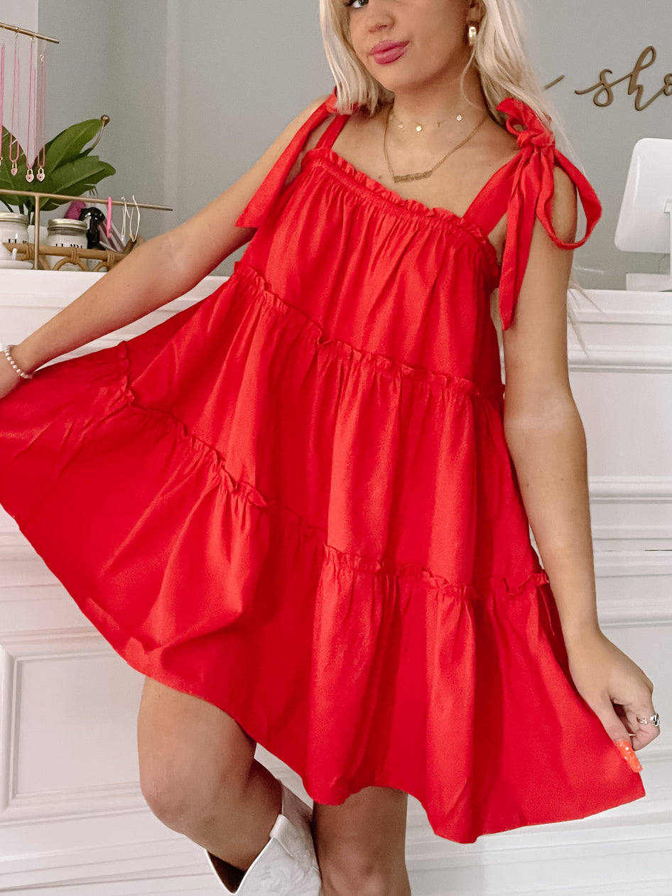 Red tiered mini dress with shoulder ties, styled casually.
