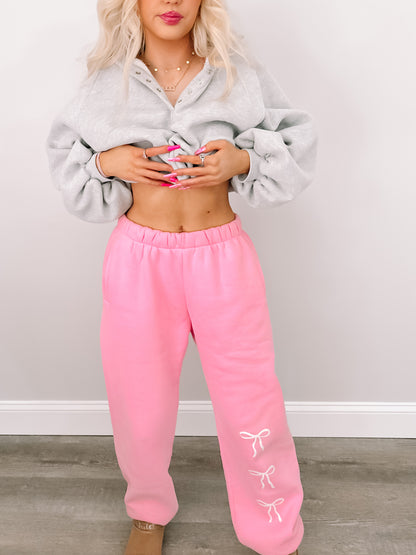 Pink sweatpants with cute bow details, styled with a gray sweatshirt.
