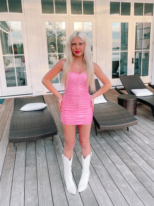 Pink mini dress with a holographic effect, worn outdoors on a patio.
