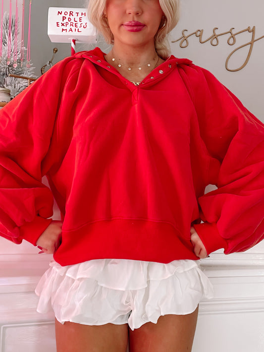 Red pullover sweatshirt with balloon sleeves, modeled with white ruffled shorts.