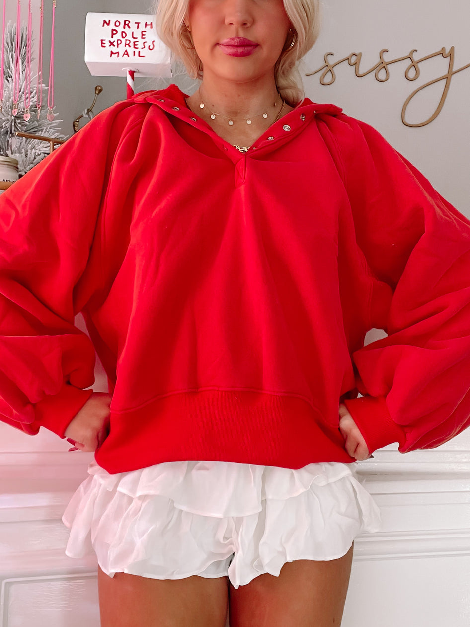 Red pullover sweatshirt with balloon sleeves, modeled with white ruffled shorts.
