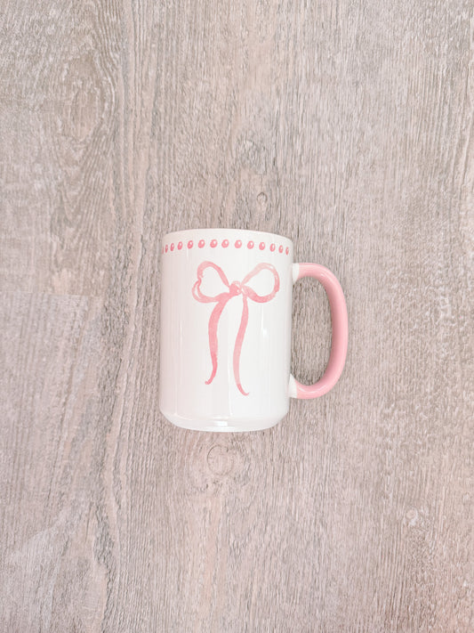 Big Bow Mug: White ceramic mug with pink bow design and pink handle.
