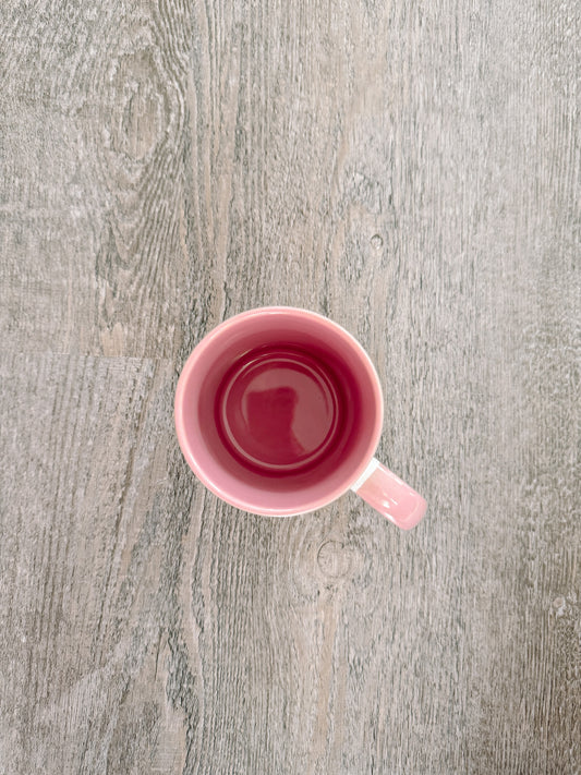 Pink mug viewed from above, empty, on a gray wood surface.
