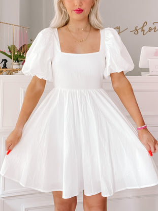 White puff-sleeve mini dress, square neckline, A-line silhouette.

