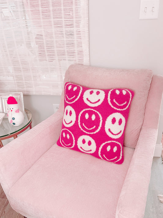 Pink armchair with a fuzzy pink and white smiley face pillow.