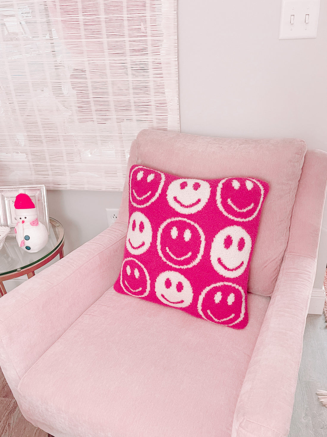 Pink armchair with a fuzzy pink and white smiley face pillow.
