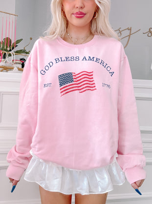 Pink "God Bless America" crewneck sweatshirt with distressed American flag graphic
