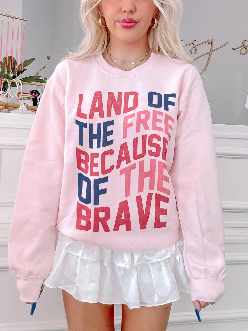 Pink crewneck sweatshirt with a patriotic message, styled with a white ruffled skirt.
