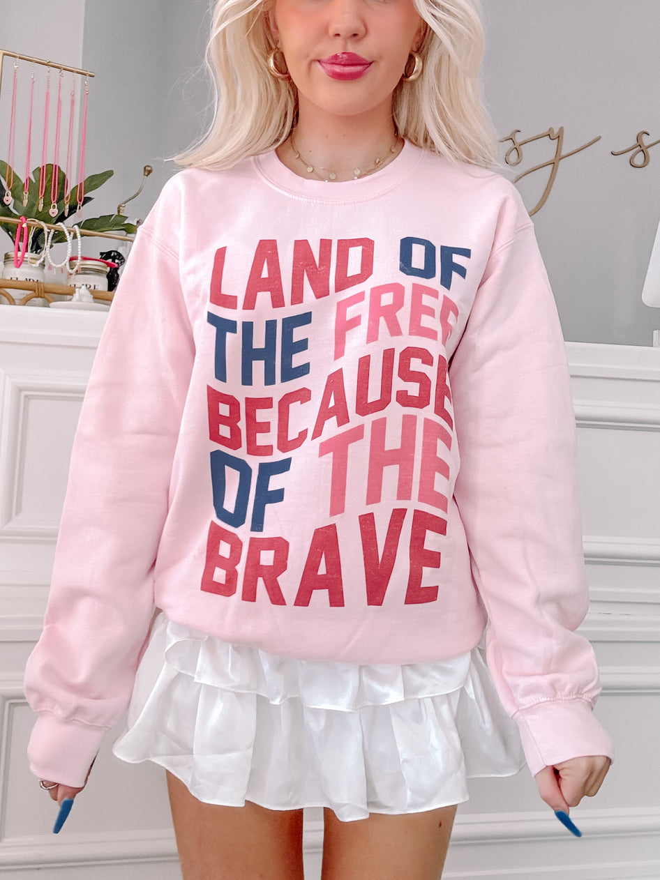 Pink Land of the Free crewneck sweatshirt with patriotic text graphic.
